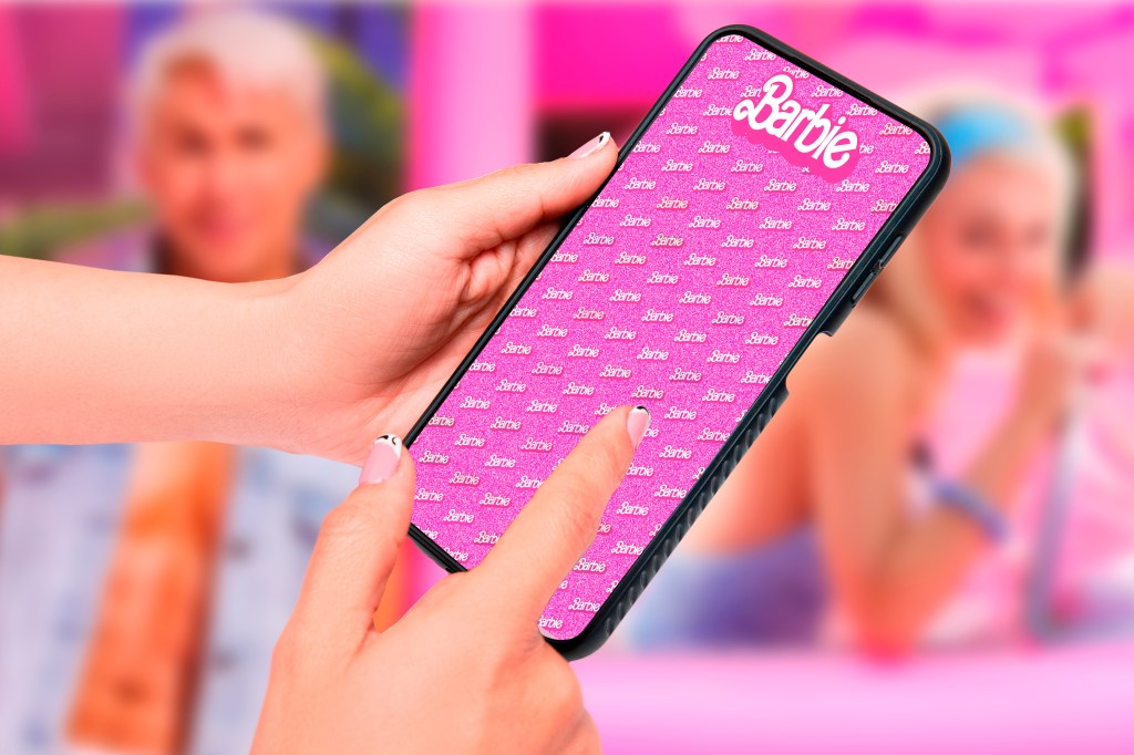 Buenos Aires, Argentina; 08-03-2023: Barbie the movie. Thematic horizontal background of woman's hands holding a cell phone that represents the success and fury for the Barbie movie. -Adobe Stock