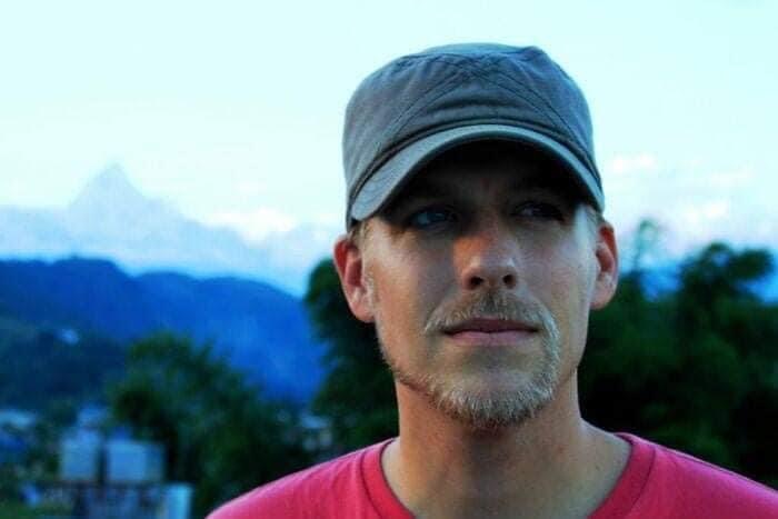 A man with a beard that wraps down around his mouth and the hooks back up around and makes his mustache.